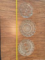 Three clear glass trays laid beside measuring tape showing size
