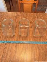 Three glass shades upright next to ruler