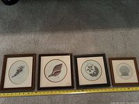 All four framed needlepoints side by side with measuring tape
