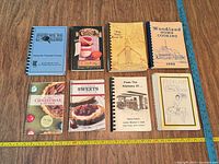 All nine cookbooks laid out with measuring tapes showing size and bindings