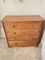 Front view of entire dresser showing medium brown finish and four drawers