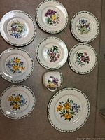 Top view of 8 floral plates and 1 mug on countertop