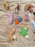 Group of plush animals including dog, ostrich, pig, hippo, bird, frog, horse