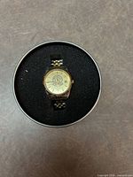 Watch in foam-lined round tin, dial and bracelet visible