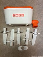 Front view of Zoku base, four sticks visible, orange super tool and white accessory