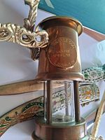 Close-up of Ferndale Coal & Mining Co plaque on brass lamp with dagger sheath enamel visible