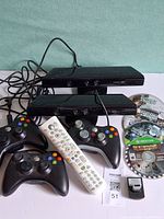 Overall group shot showing two Kinect sensors, three controllers, four game discs and remote