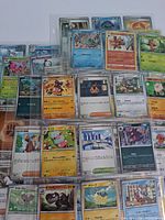 Multiple binder pages filled with assorted Pokémon cards, mix of languages and rarities