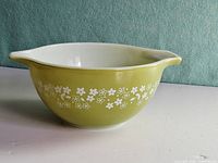 Side view showing green exterior, white daisy pattern, handle and spout