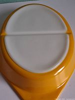 Bottom view of yellow Pyrex divided casserole showing white interior divider