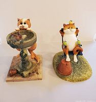 Front view of both figurines: cat with bird bath and cat in deck chair