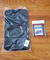 Front view of jewelry roll in bag beside packaged travel wallet