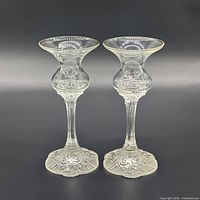 Front view of both clear pressed glass candle holders