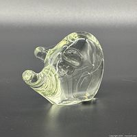 side view of glass pig figurine showing overall shape and yellow-green tint