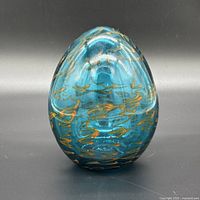Front view of teal glass egg showing overall shape and swirl pattern