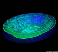 Bowl under blacklight showing uranium fluorescence and embossed poinsettia pattern