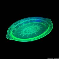 Top view of glowing green oval uranium glass platter displaying Cameo pattern and rim detail