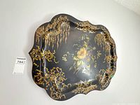 Front view of scalloped black tray with floral and gold design