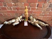 two plastic cherubs and resin Venus torso on table