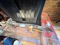 Top view of fireplace tools on hearth showing shovel, poker, tongs, stand