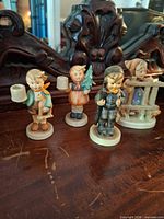 Group shot of four Goebel Hummel candleholder figurines on wooden surface