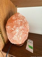 Full view of Himalayan pink salt lamp on wood base with power cord visible