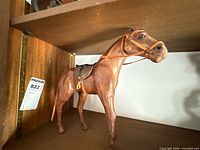 Left side view of leather horse figurine showing saddle, bridle, reins and overall condition