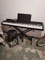 Keyboard on stand with stool and pedal visible