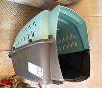 Side angled view of two-tone plastic pet carrier showing ventilation holes and overall condition