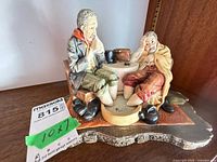Front view of Naturecraft Doctor's Dilemma figurine showing two men seated at table on shaped base