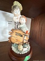 Front view of porcelain children figurine on barrel, wood base visible