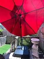 Red patio umbrella opened, showing canopy, ribs, and pole