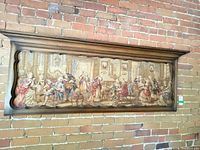Full view of long framed Rococo tapestry against brick wall