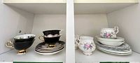 Overview showing black and white floral teacups with stacked plates