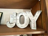 Front view of JOY marquee letters on shelf
