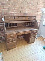 Front view of oak roll-top desk showing drawers, tambour, interior cubbies