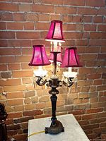 Full view of bronze table lamp with four purple shades on marble surface