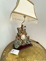 Full lamp showing shade, cherub body, clock face on wood base
