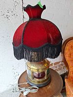 Full view of brass nautical lamp with red velvet fringe shade