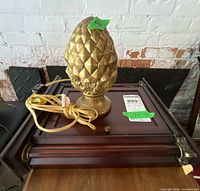 Gold pineapple lamp resting on wood key cabinet
