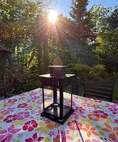 Full view of black metal lantern on floral tablecloth outdoors