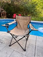 Front view of tan kids folding camp chair beside pool