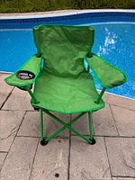 Front view of bright green Ozark Trail folding kids chair by pool