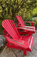 Two red wooden Adirondack chairs showing overall appearance and paint wear