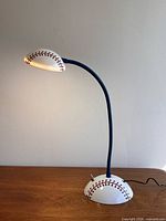 Full view of lamp showing baseball base, blue gooseneck, shade illuminated
