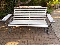 Full front view of glider bench showing wood slats and cast iron frame