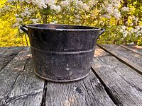 Front view of black metal tub showing overall shape and exterior wear