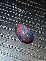 Top view of oval black opal showing multicolor play-of-color.
