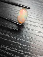 Front view of oval opal cabochon held in tweezers