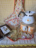 Group view of all items including apron, teapot, mugs, trivet and strainer